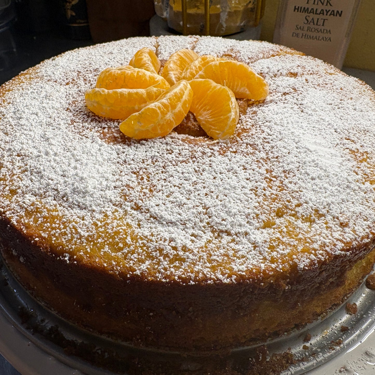 Classic olive oil cake dusted with powdered sugar and topped with fresh mandarin slices.