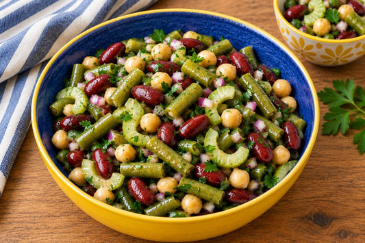 Three bean salad with green beans, kidney beans, chickpeas, tomatoes, and herbs served in colorful bowls.