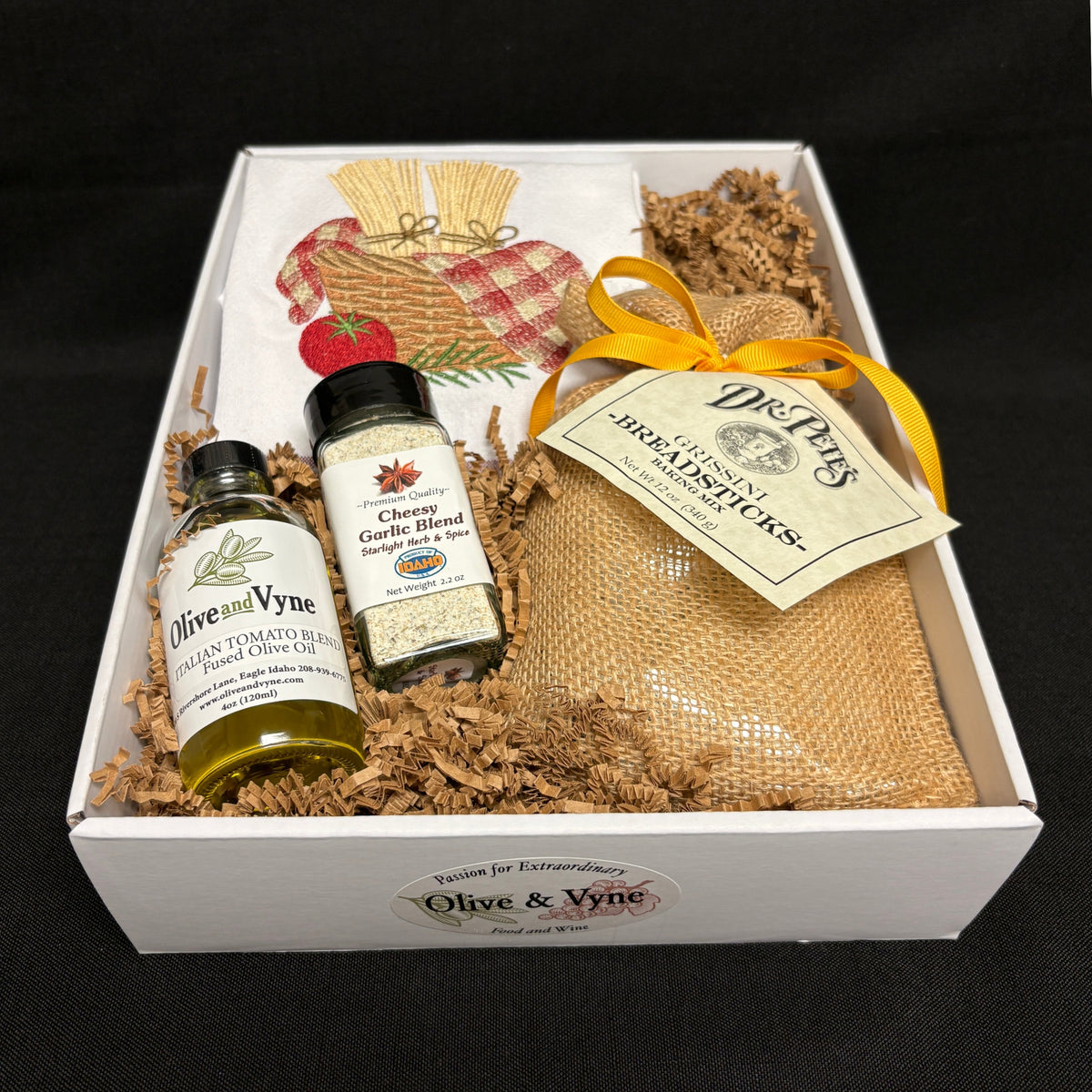 Open 9x12 Breadstick Mix gift box with Dr. Pete’s Grissini Mix, Italian Tomato Blend Olive Oil, Cheesy Garlic Blend, and embroidered cotton towel.