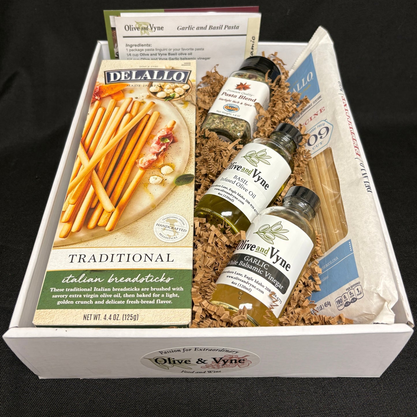 Open 9x12 Garlic & Basil pasta gift box with Olive & Vyne oils, DeLallo fettuccine, breadsticks, Pasta Blend seasoning, and recipe card.