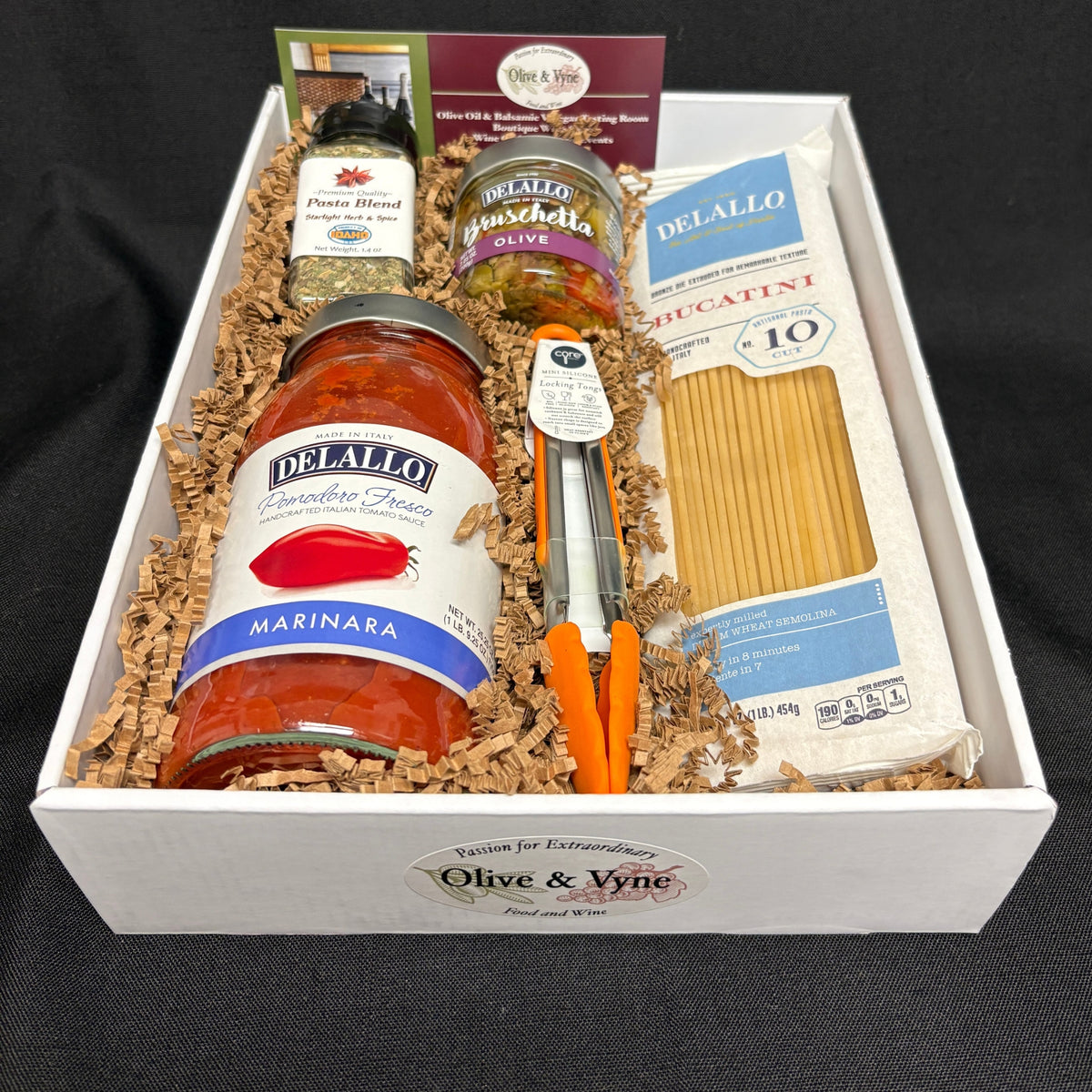 Open 9x12 Marinara Pasta Lovers gift box with DeLallo Bucatini, marinara, olive bruschetta, Starlight Pasta Blend, and mini locking tongs.