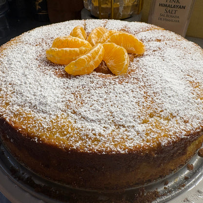 Classic olive oil cake dusted with powdered sugar and topped with fresh mandarin slices.