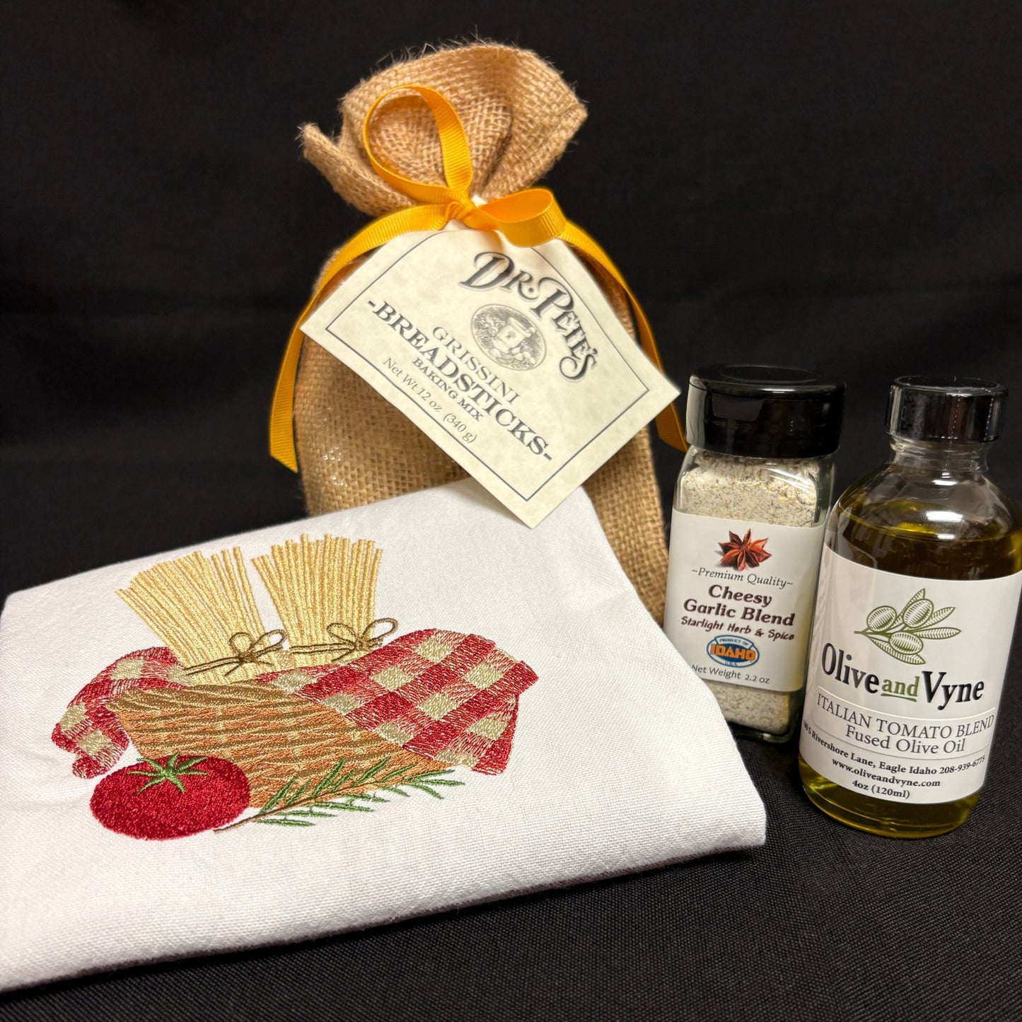 Dr. Pete’s Grissini Breadsticks Baking Mix with Italian Tomato Blend Fused Olive Oil, Cheesy Garlic Blend, and embroidered cotton kitchen towel.